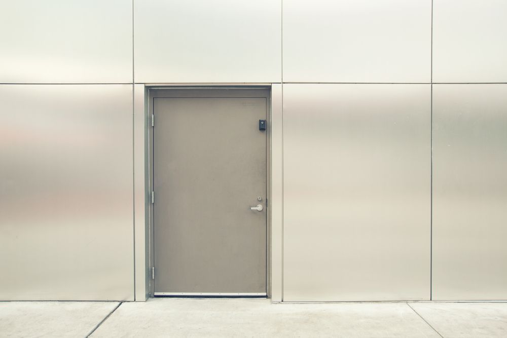 Hay una puerta en el medio de una pared de acero inoxidable.