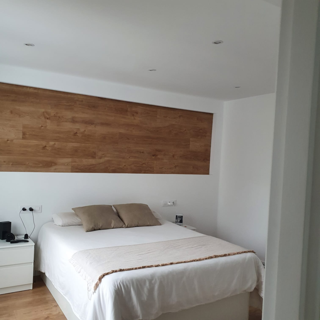 Un dormitorio con una cama y una pared de madera.