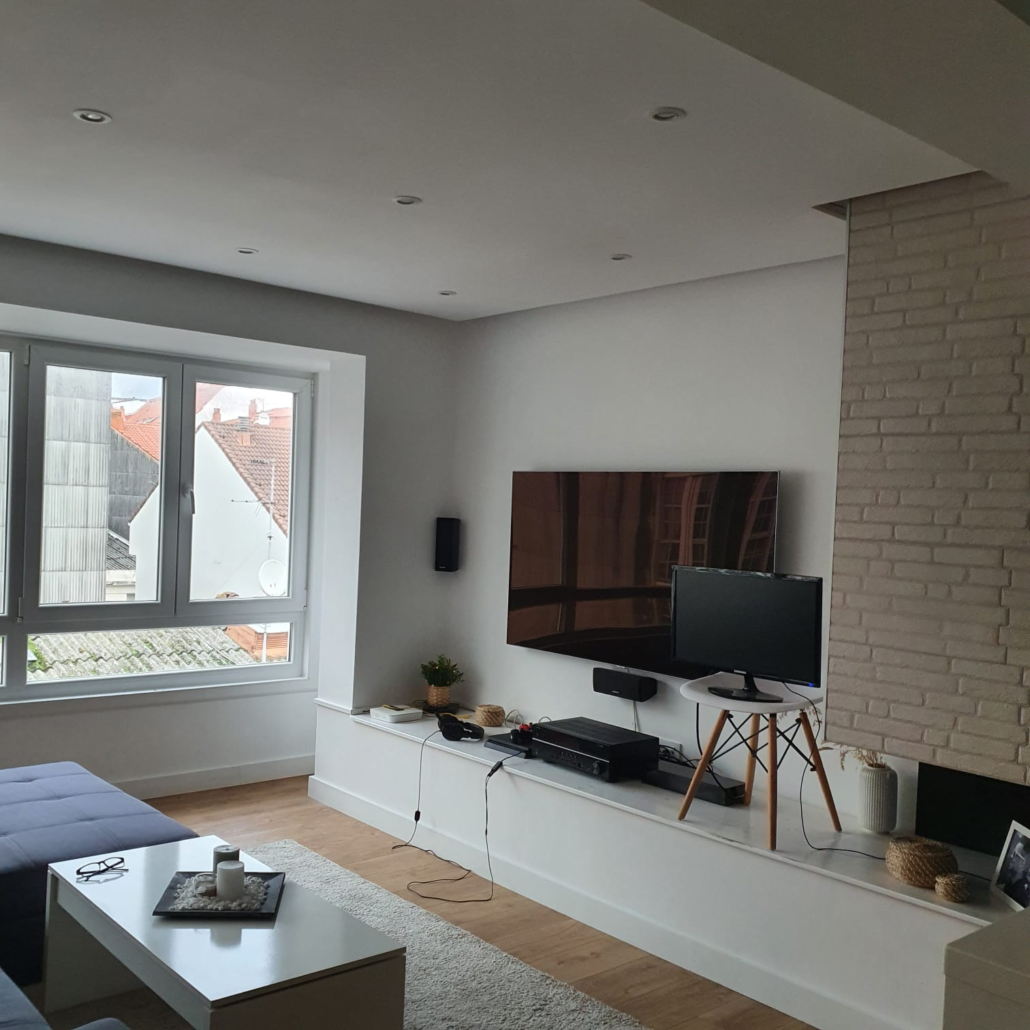 Una sala de estar con un televisor de pantalla plana en la pared.