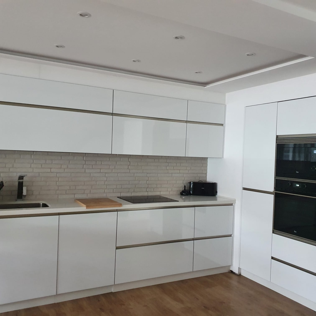 Una cocina con gabinetes blancos y piso de madera.