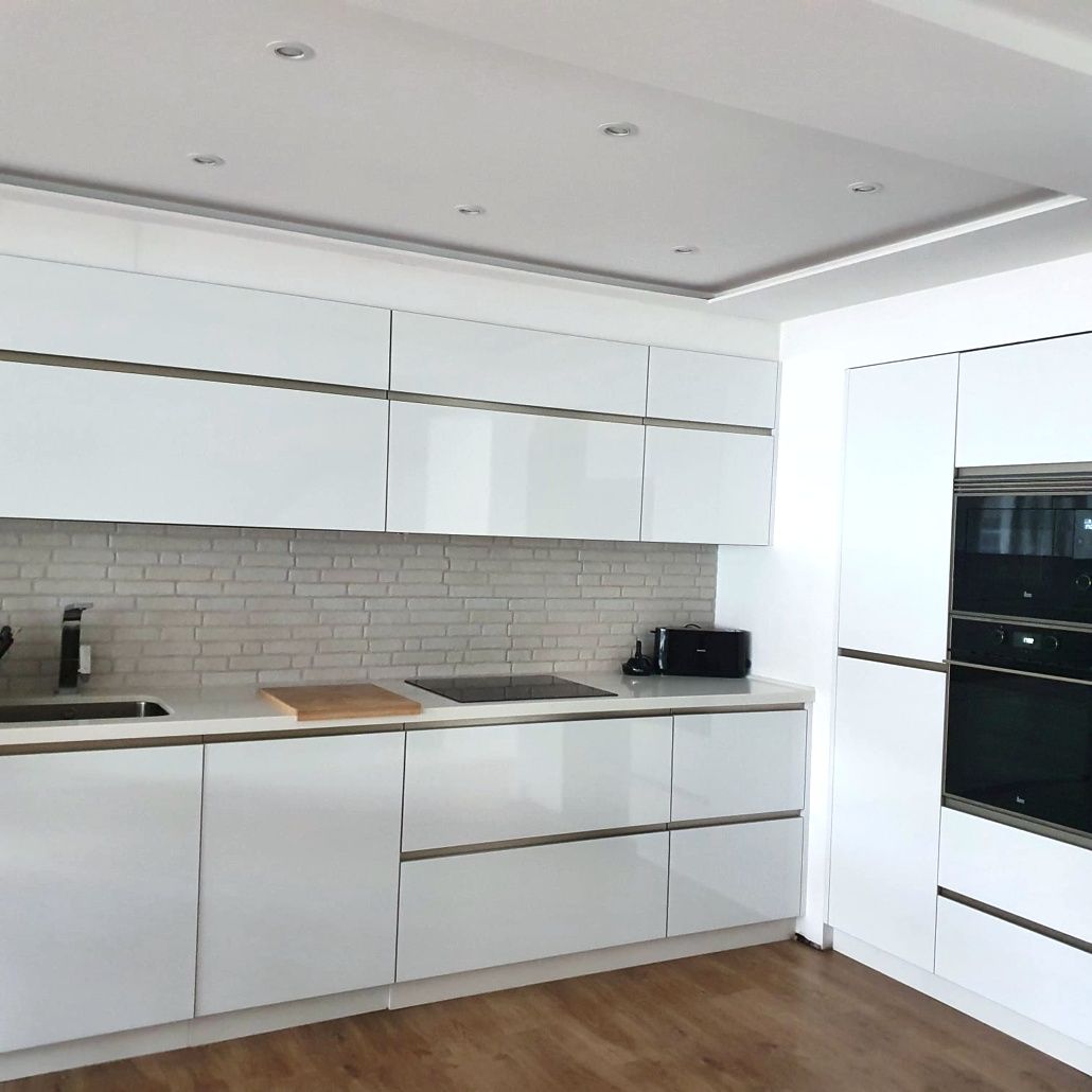 Una cocina con gabinetes blancos y piso de madera.