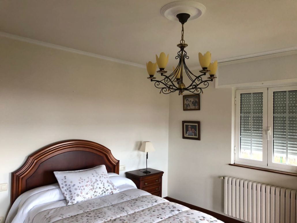 Un dormitorio con una cama y una lámpara de araña colgando del techo.