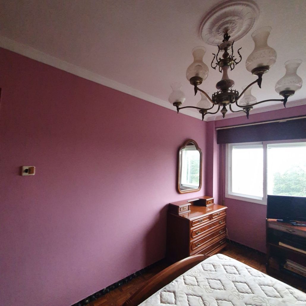 Un dormitorio con paredes rosas y una lámpara de araña colgando del techo.