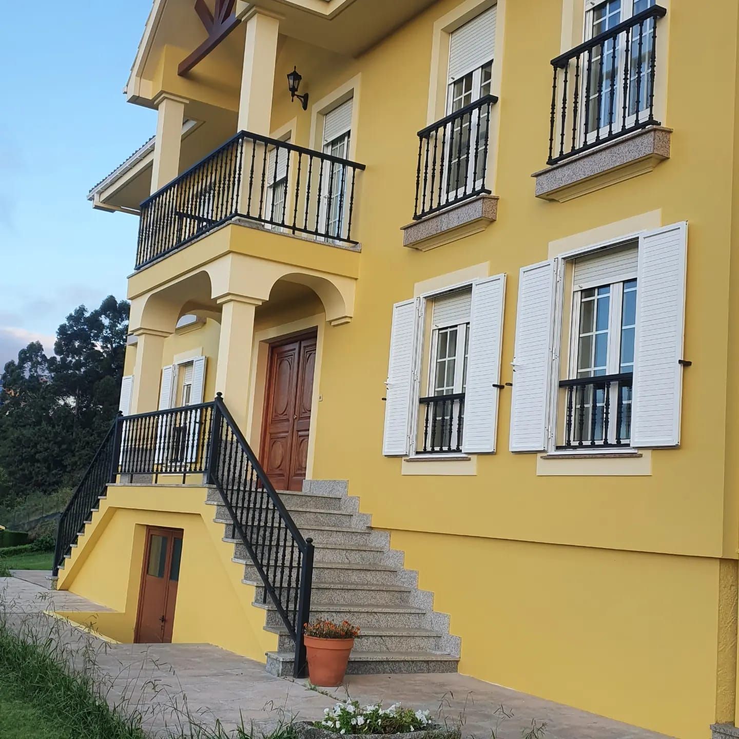 Una casa amarilla con persianas y escaleras blancas
