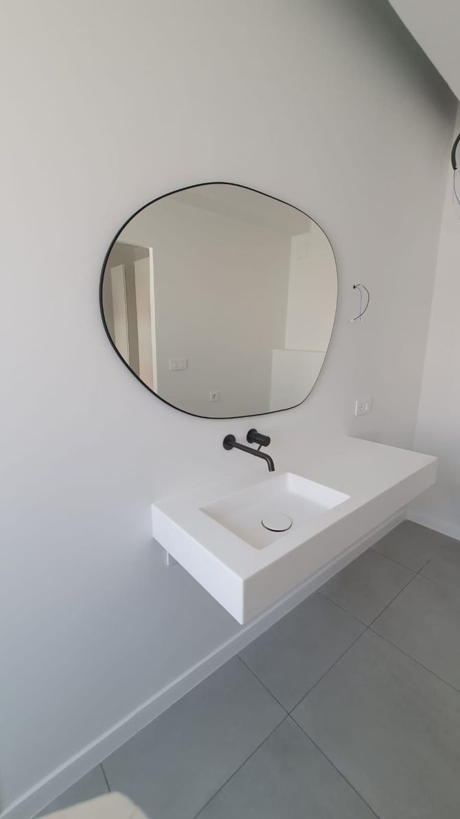 Un lavabo de baño con un espejo redondo encima.