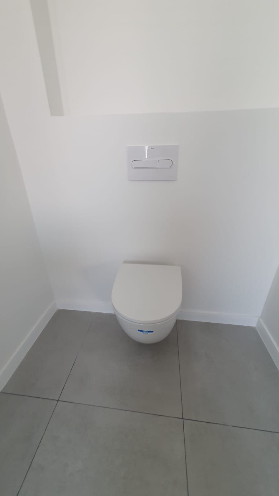 Un inodoro está colgado de la pared en un baño.