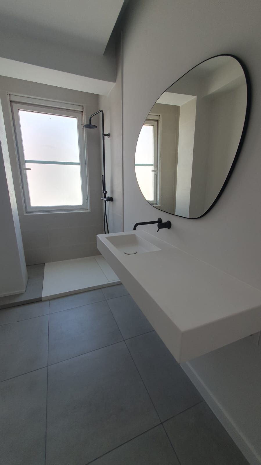 Un baño con lavabo, espejo y ducha.