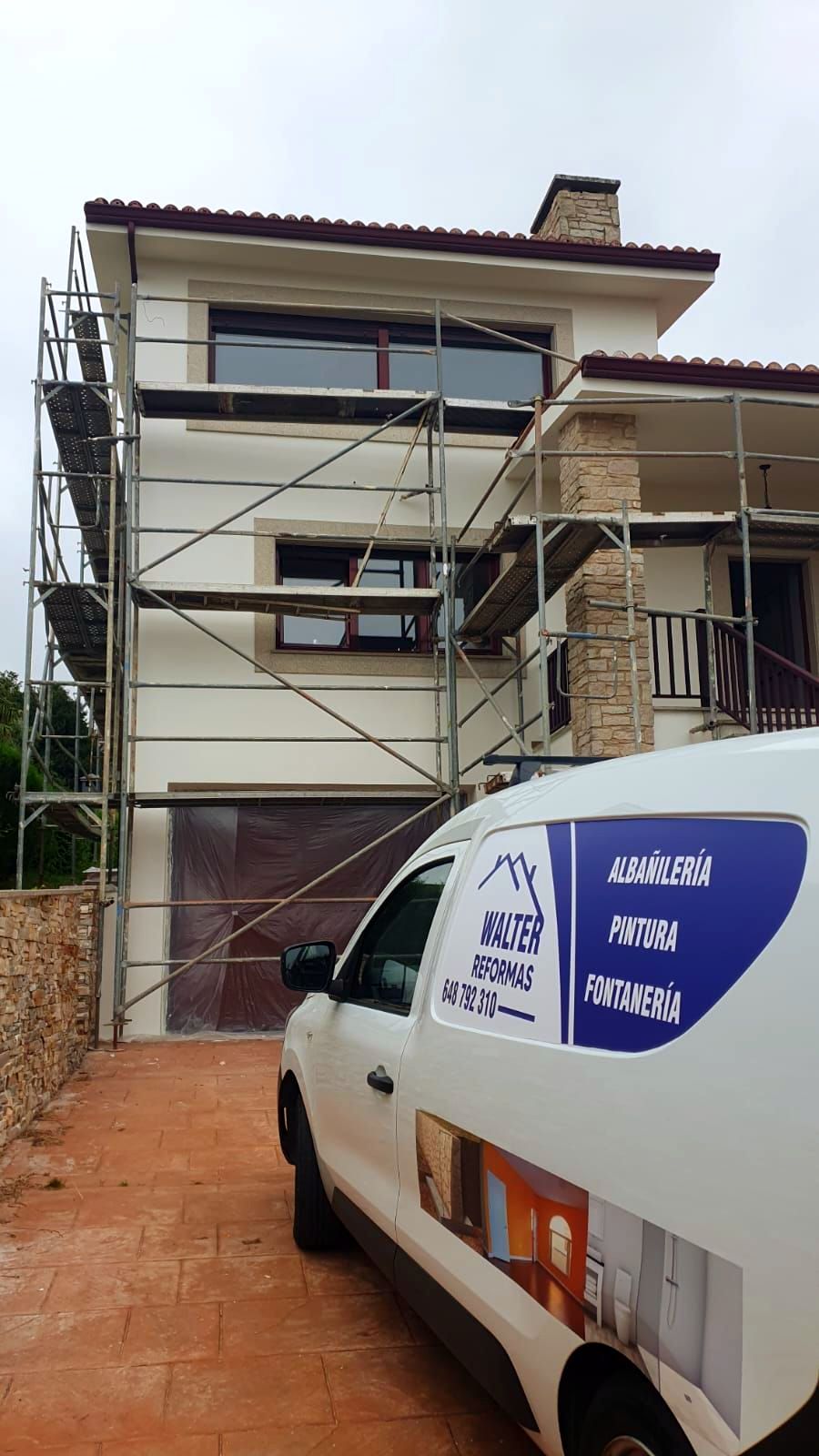 Una camioneta blanca está estacionada frente a una casa en construcción.