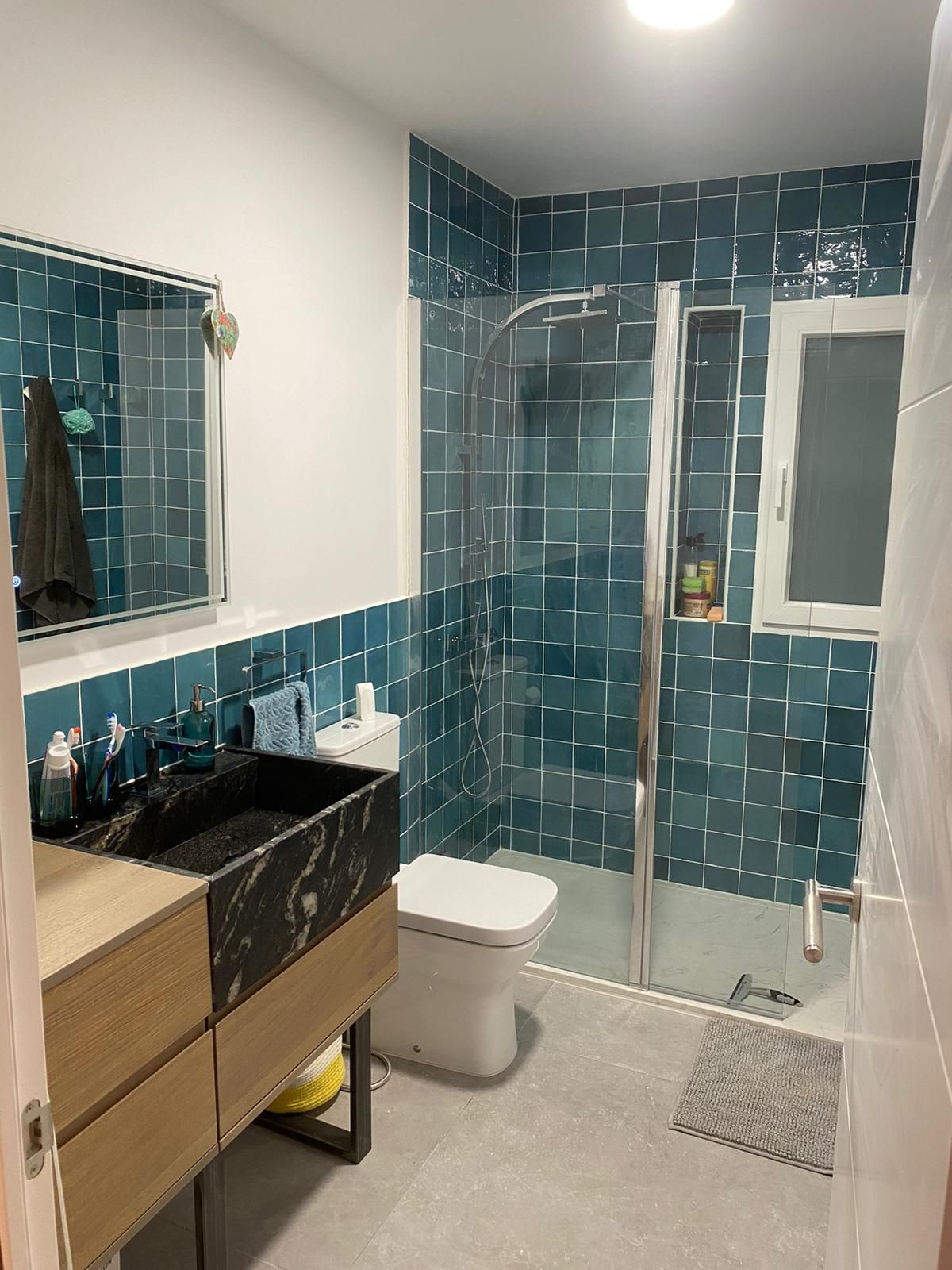 Un baño con lavabo, inodoro, ducha y espejo.