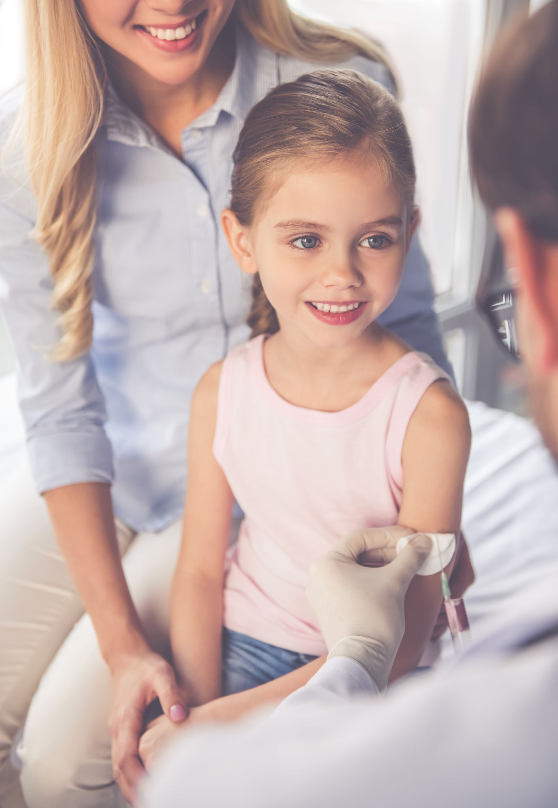 Une fillette reçoit une injection d'un médecin, en présence de sa mère.