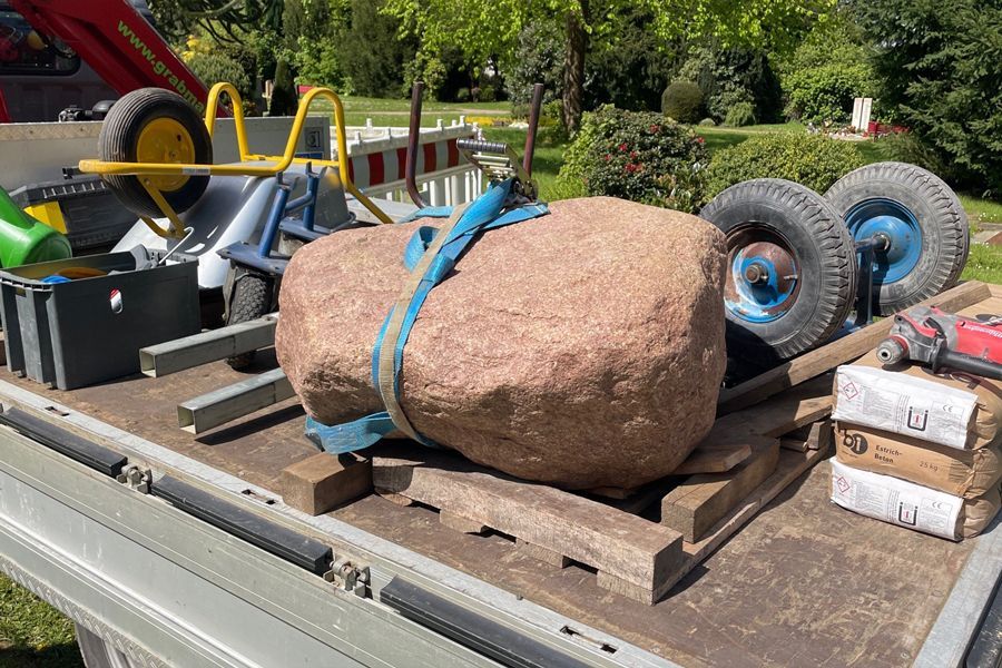 A large rock is sitting on the back of a truck.