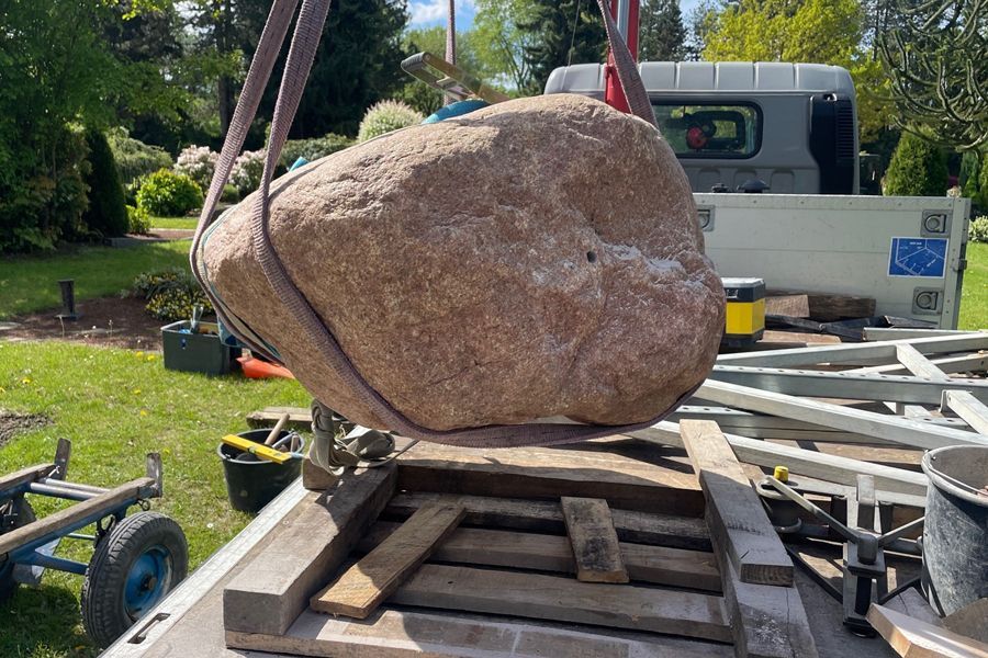 A large rock is sitting on the back of a truck.