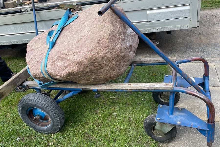 A large rock is sitting on the back of a truck.