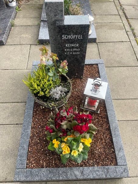 Ein Grab mit Blumen und einer Laterne darauf.