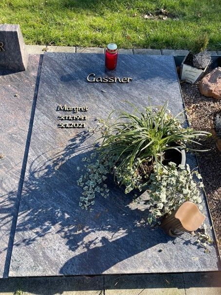 Ein Grab mit einer Kerze und Topfpflanzen darauf.