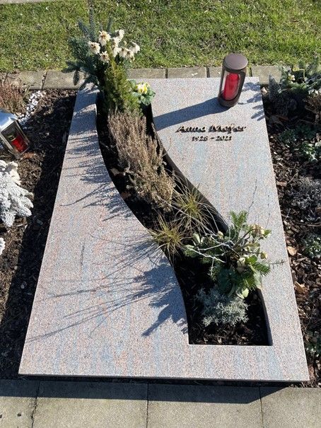 Ein Grab mit Blumen und einer Kerze darauf