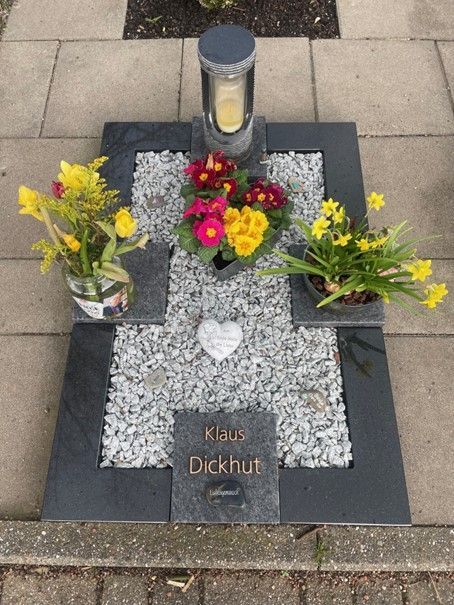 Ein Grab mit Blumen und einer Kerze darauf