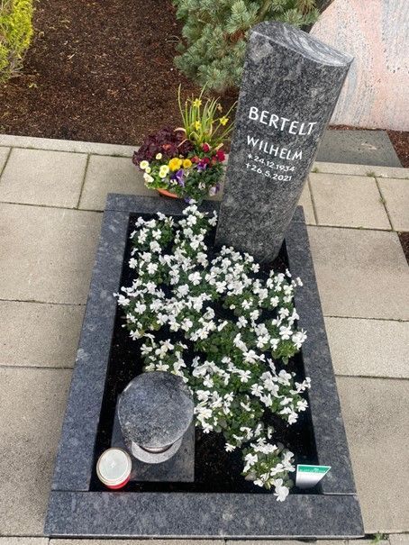 Ein Grab mit Blumen und einer Kerze darauf