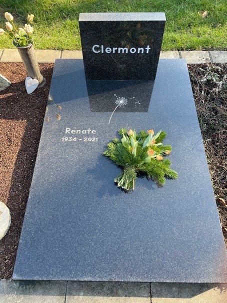 Ein Grabstein für Renate Clermont mit Blumen darauf