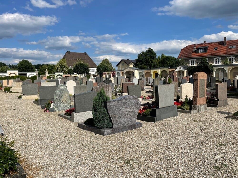 Ein Friedhof mit vielen Grabsteinen und einem Gebäude im Hintergrund  | ZIESCHE // GRABMALE