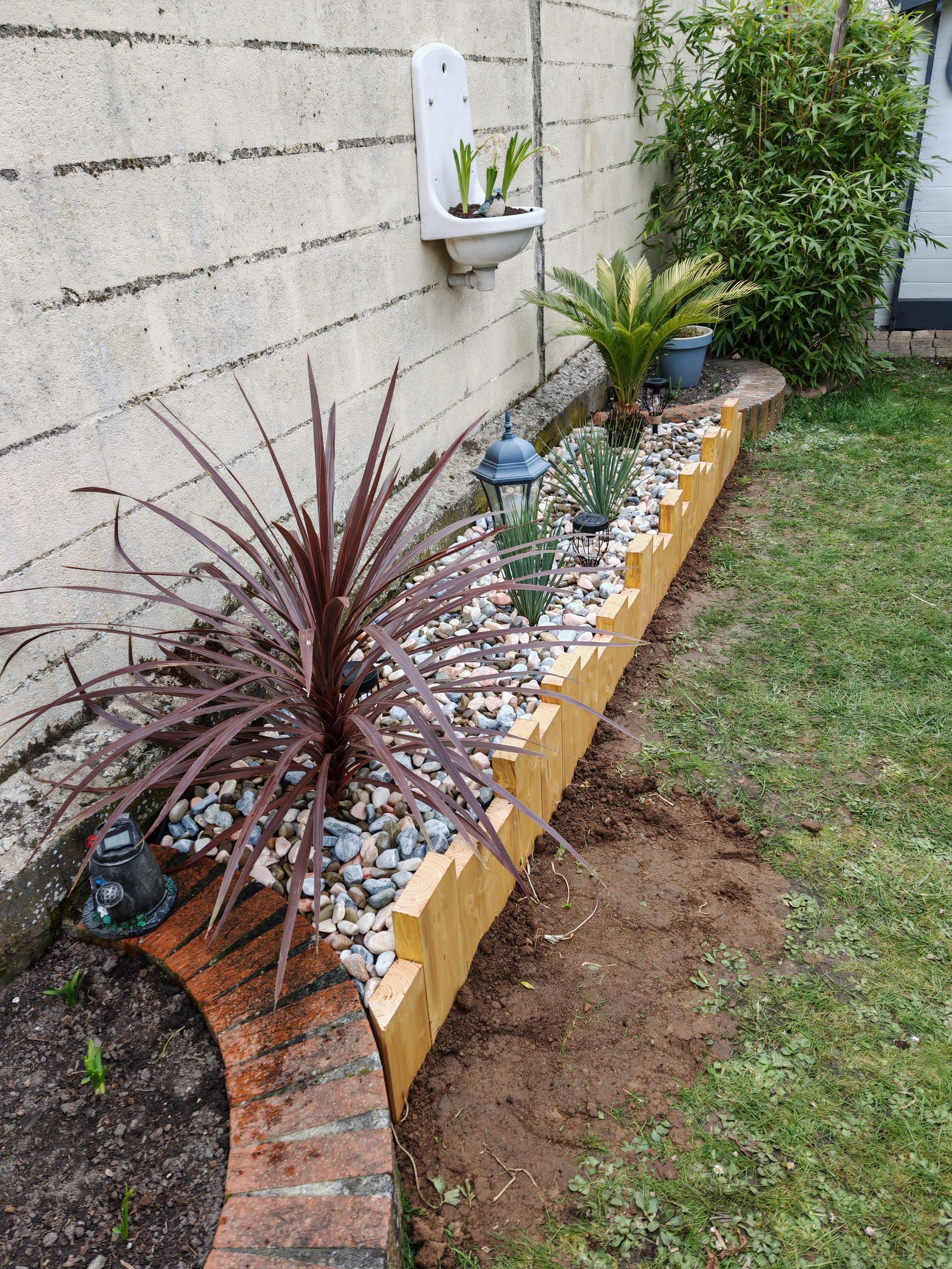 Un homme utilise une tronçonneuse pour tailler un grand arbre près d'un bâtiment. Ciel d'un bleu éclatant.