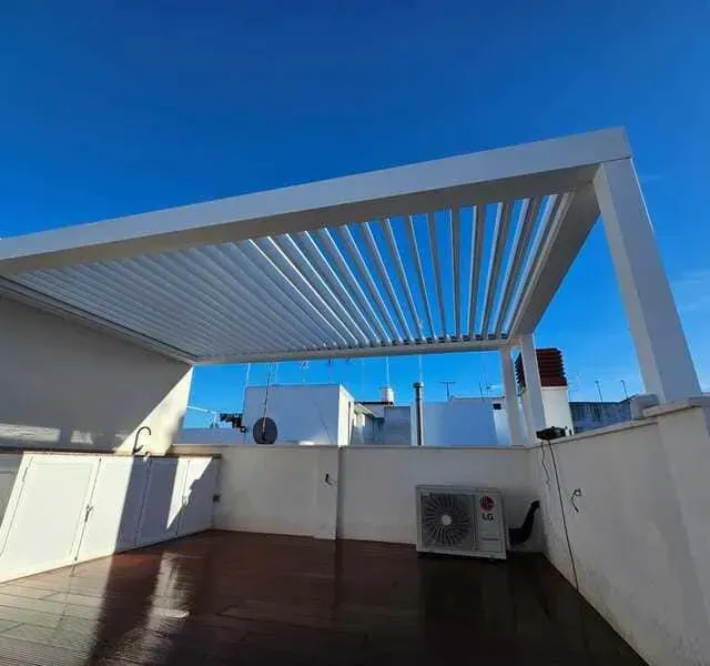 Una terraza en la azotea con pérgola y aire acondicionado.