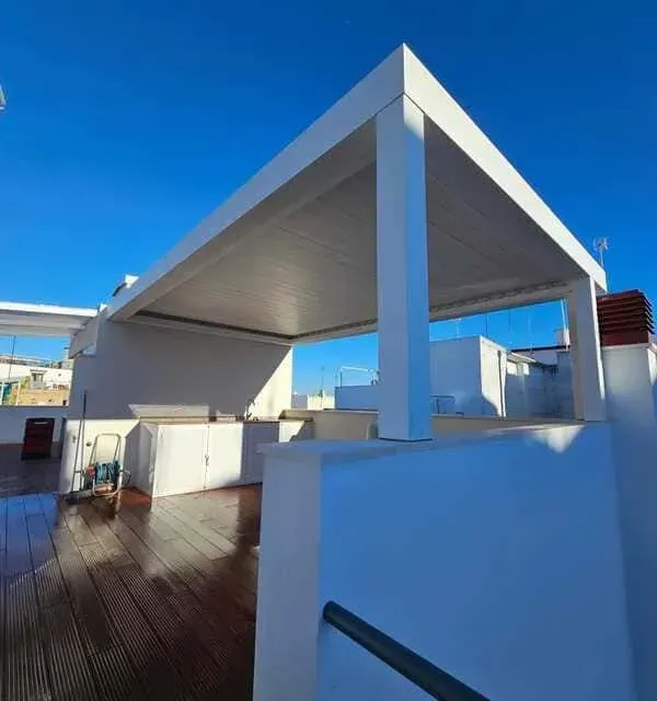 Una pérgola blanca se encuentra sobre una plataforma de madera.