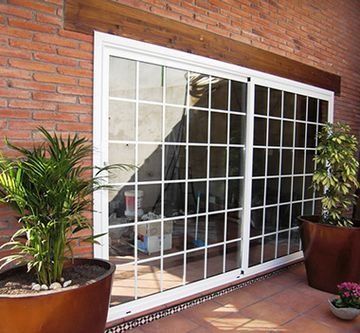 Un edificio de ladrillo con una puerta corrediza de vidrio y plantas en macetas en el frente.