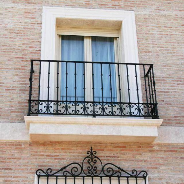 Un balcón con barandilla de hierro forjado en un edificio de ladrillo.