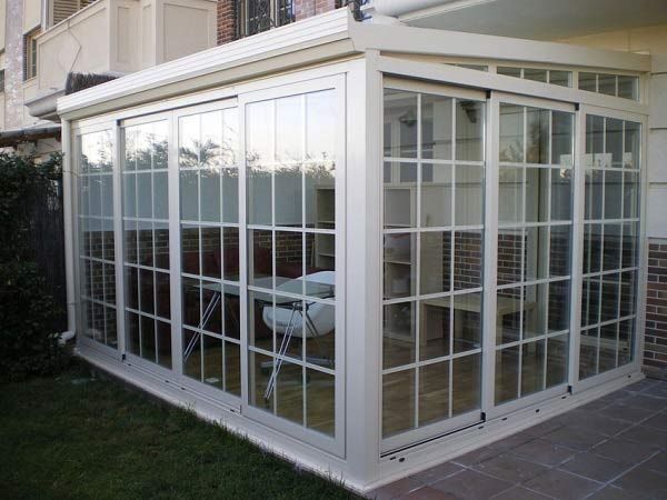 Una habitación con muchas ventanas y una mesa y sillas en ella.