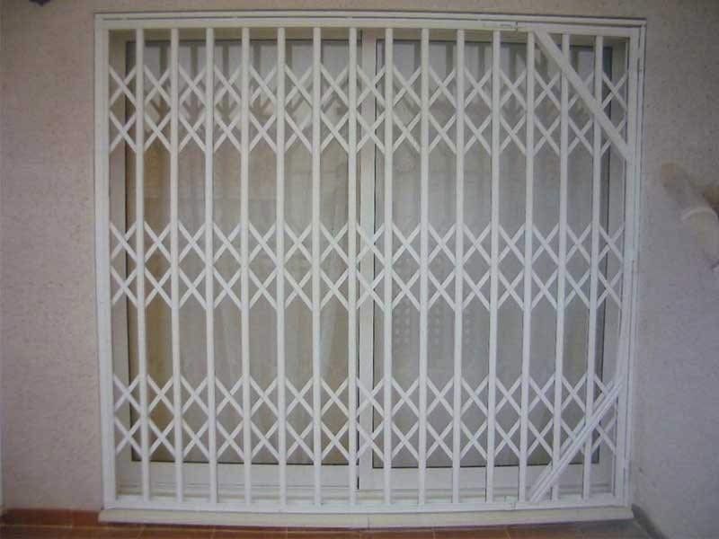 Una puerta de metal blanco está sobre una puerta corrediza de vidrio.