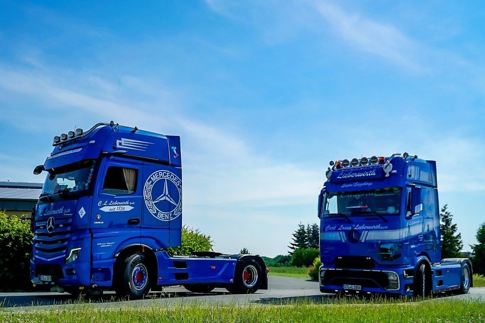 Zwei blaue Sattelschlepper parkten auf einer Wiese unter strahlend blauem Himmel