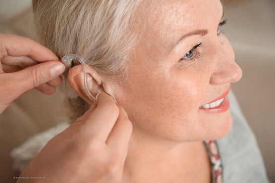 Eine Frau bekommt ein Hörgerät angelegt