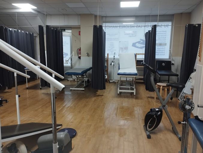 Una sala de fisioterapia vacía con una cinta de correr y una bicicleta