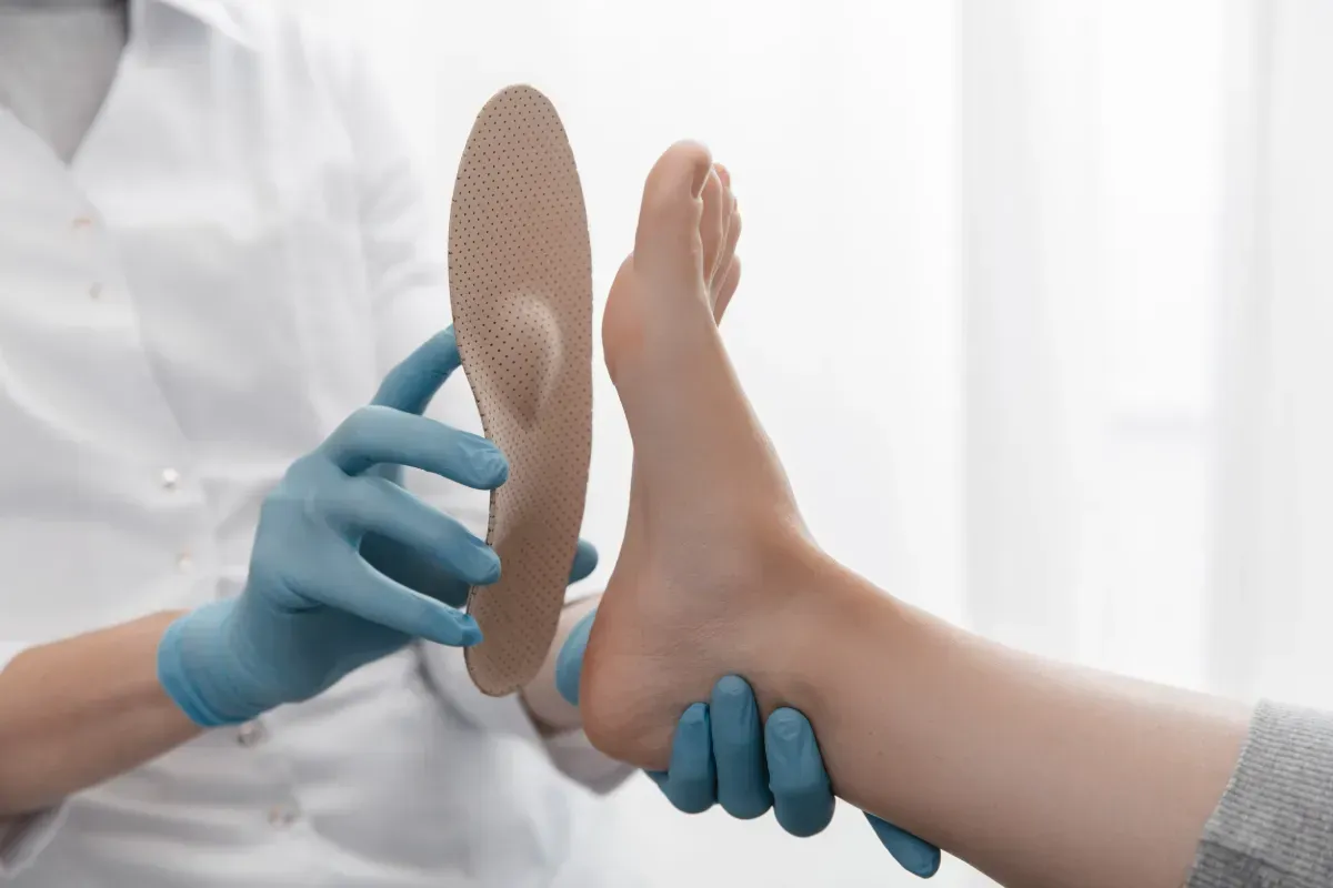 Un médico está examinando el pie de un paciente con un par de plantillas.