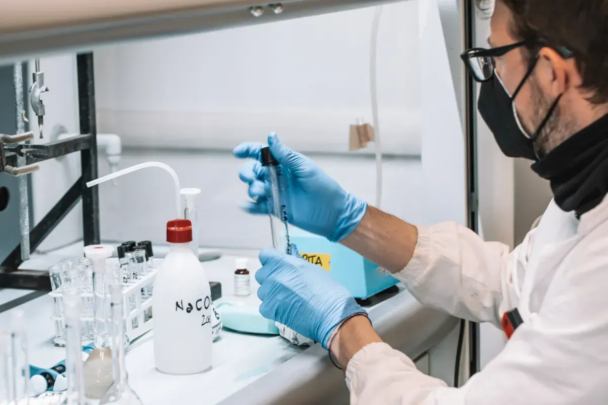Un hombre que lleva una máscara y guantes está trabajando en un laboratorio.