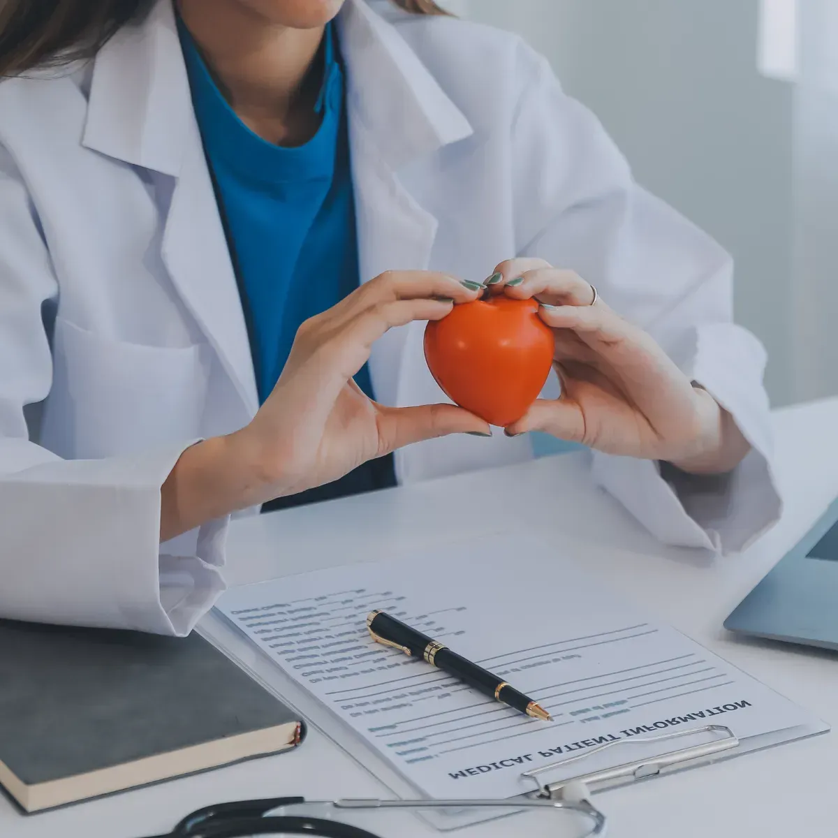 Una doctora sostiene un corazón naranja en sus manos.