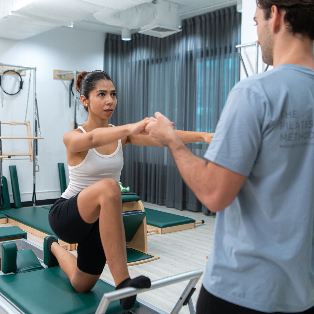 Un hombre está ayudando a una mujer a hacer ejercicios en una máquina de pilates.