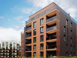 Großes rotes Wohngebäude vor blauem Himmel