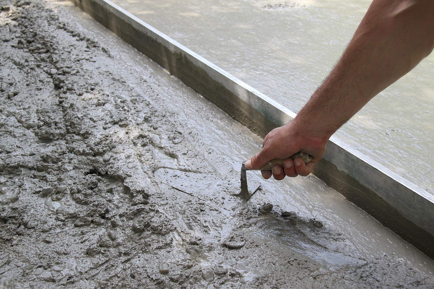 Un professionnel utilise un truelle sur du ciment frais