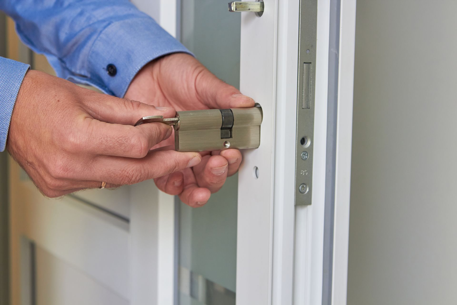 Une personne remplaçant une serrure dans une porte en PVC.