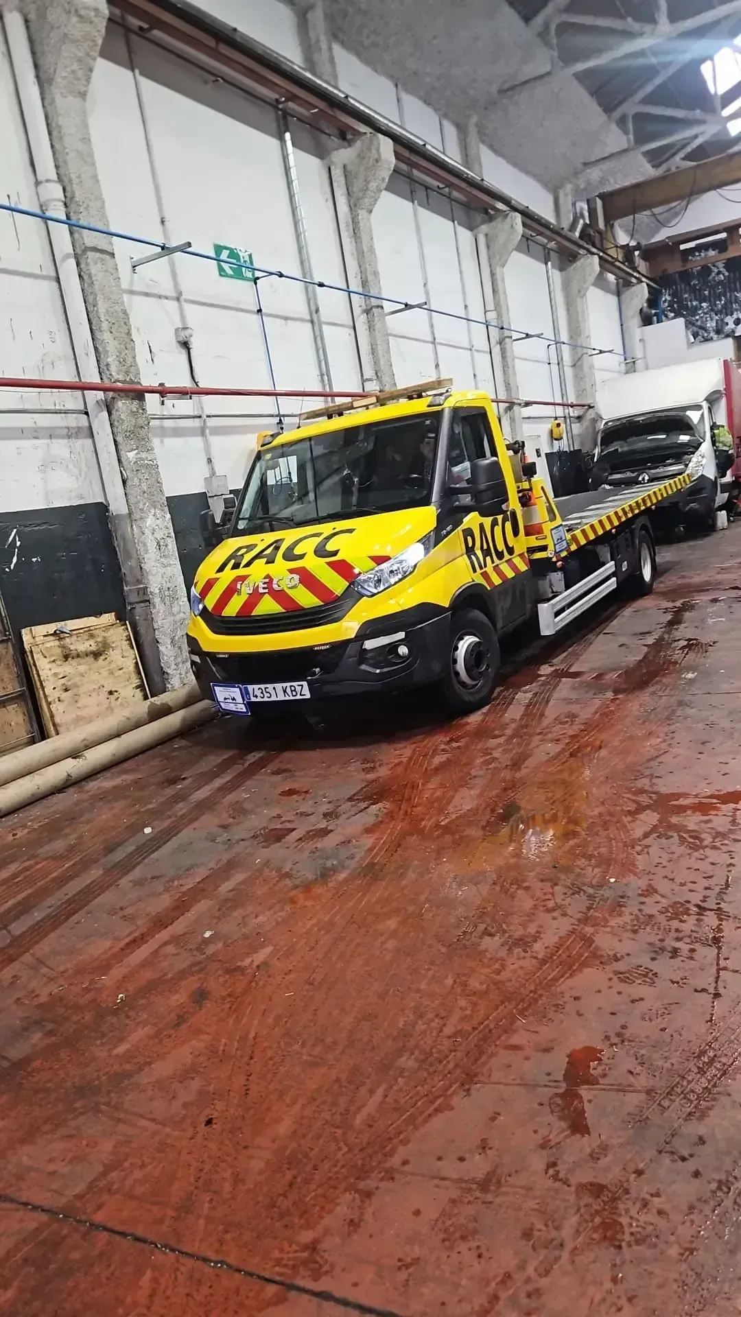 Grúa amarilla dentro de un garaje. La grúa tiene el logo 