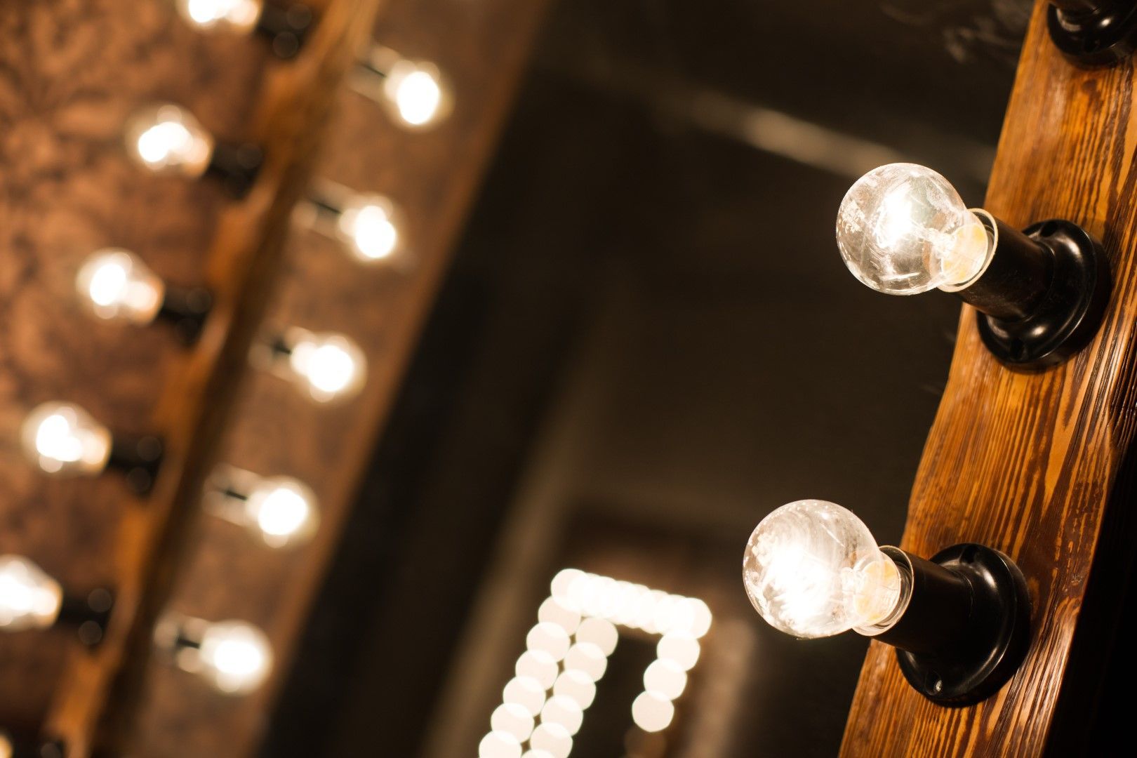 Miroir de courtoisie à cadre en bois avec plusieurs ampoules éclairées, éclairage chaleureux.