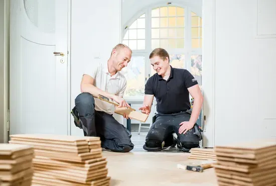 Gemütliches Sofa mit vielen bunten Kissen in Türkis- und Lilatönen vor einer Wand mit verschiedenen gerahmten Bildern.