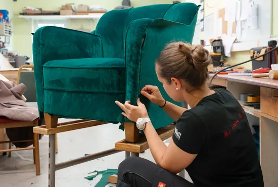 Nahaufnahme eines edlen, dunkelblauen Jacquard-Stoffes mit erhabenem floralem Muster auf gold-beigem Grund.