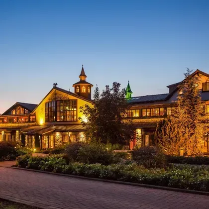 Außenansicht eines prächtigen Hotelgebäudes bei Dämmerung mit stimmungsvoller Außenbeleuchtung und Türmchen-Architektur.