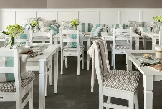 Ein helles Bistro oder Restaurant mit weißen Holzstühlen