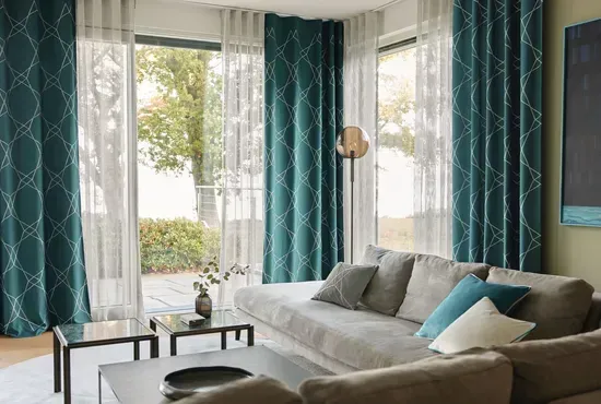 Ein Wohnzimmer mit großzügigen, petrolfarbenen Vorhängen, die einen eleganten Kontrast zum hellen Sofa bilden.