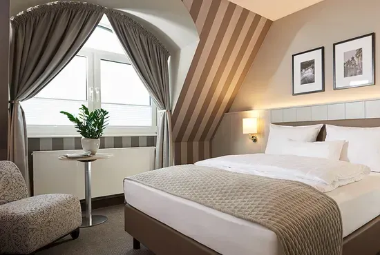 Ein gemütliches Schlafzimmer mit gestreifter Tapete, perfekt abgestimmten Vorhängen und einem fertig bezogenen Doppelbett.