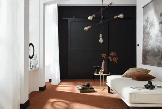 Ein heller Boden in einem modernen Raum mit schwarzer Akzentwand und minimalistischer Möblierung.